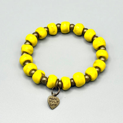 Vibrant yellow handmade bead bracelet with 'Made with Love' heart charm, celebrating artisan craftsmanship.